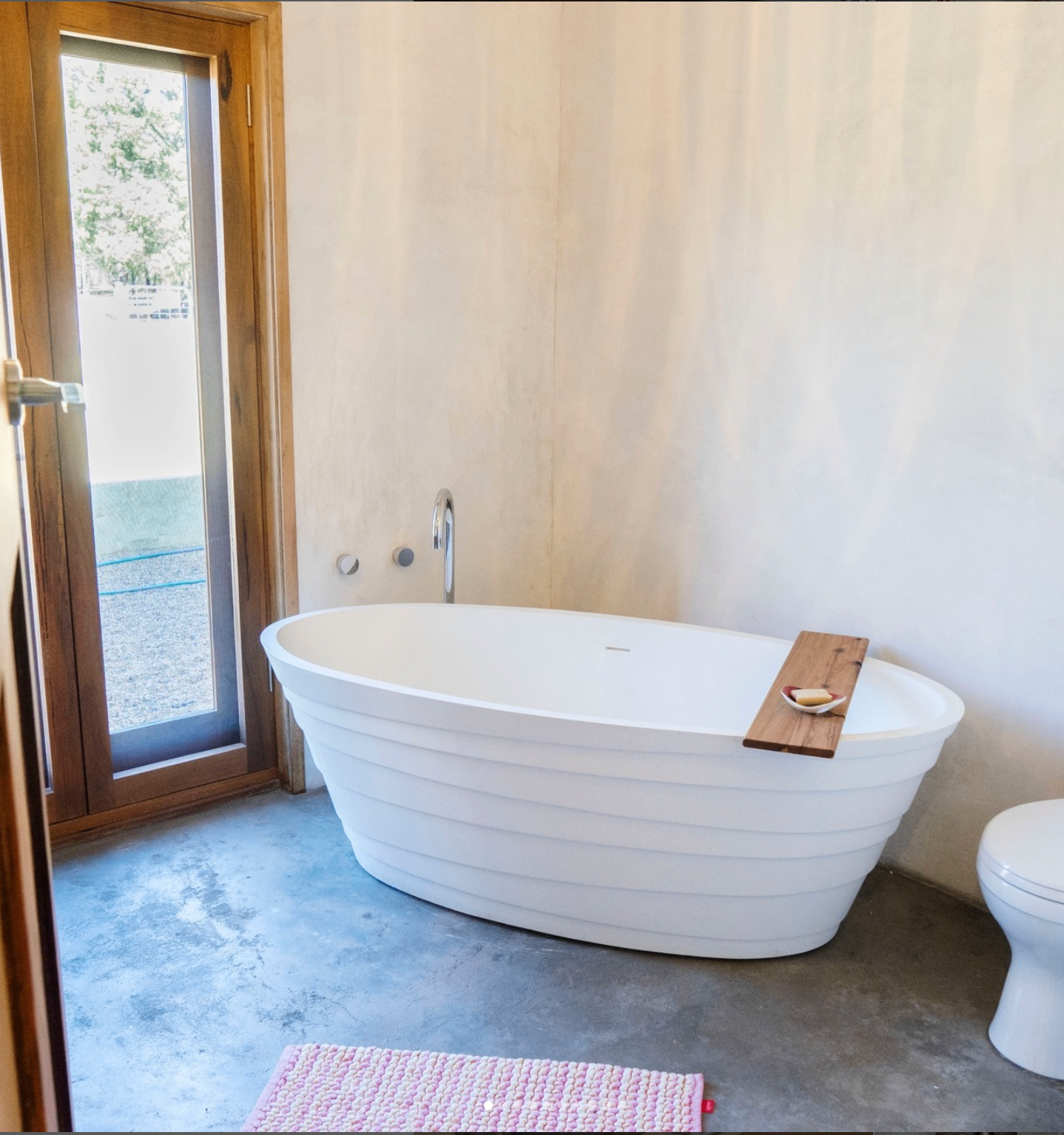 Bathroom with freestanding tub, polished concrete floor and timber-framed door