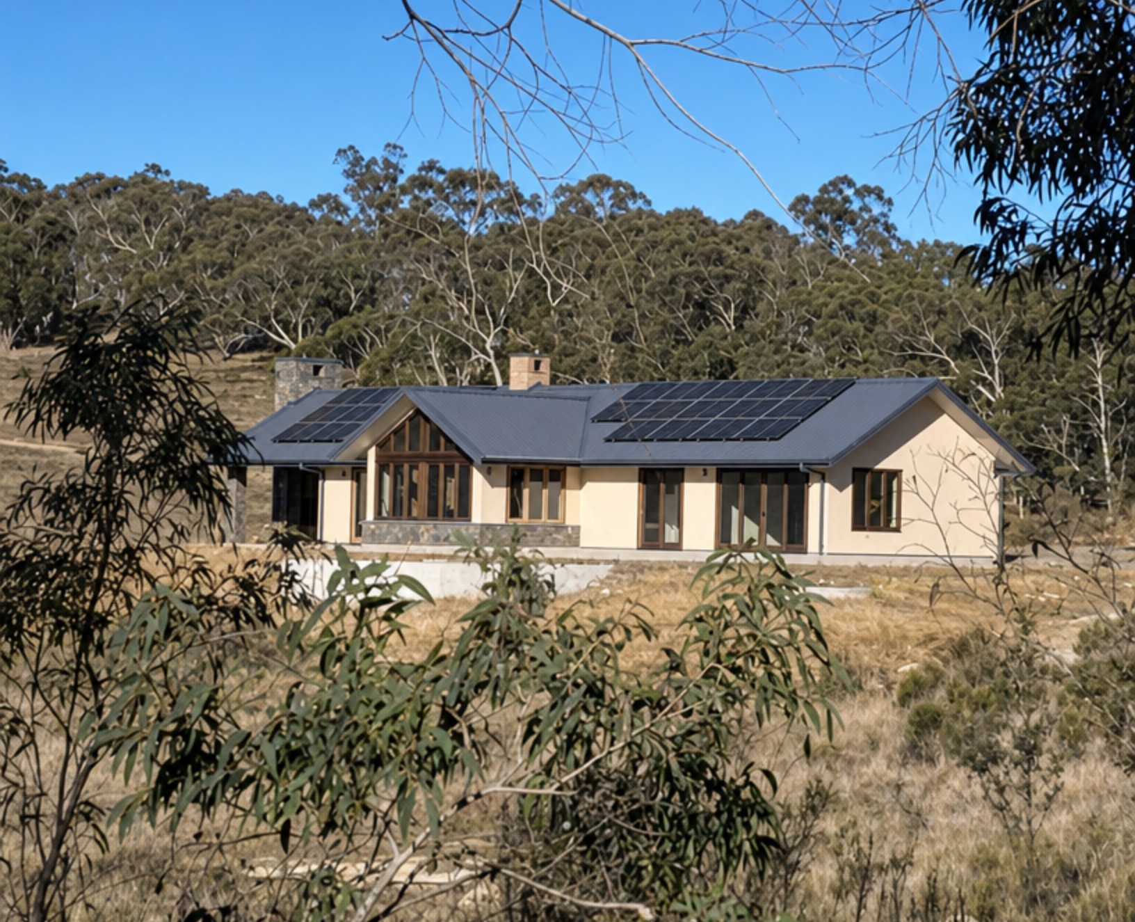 Viva Panel rural home with gabled metal roof, solar panels, rendered straw walls and timber-framed windows set in bushland